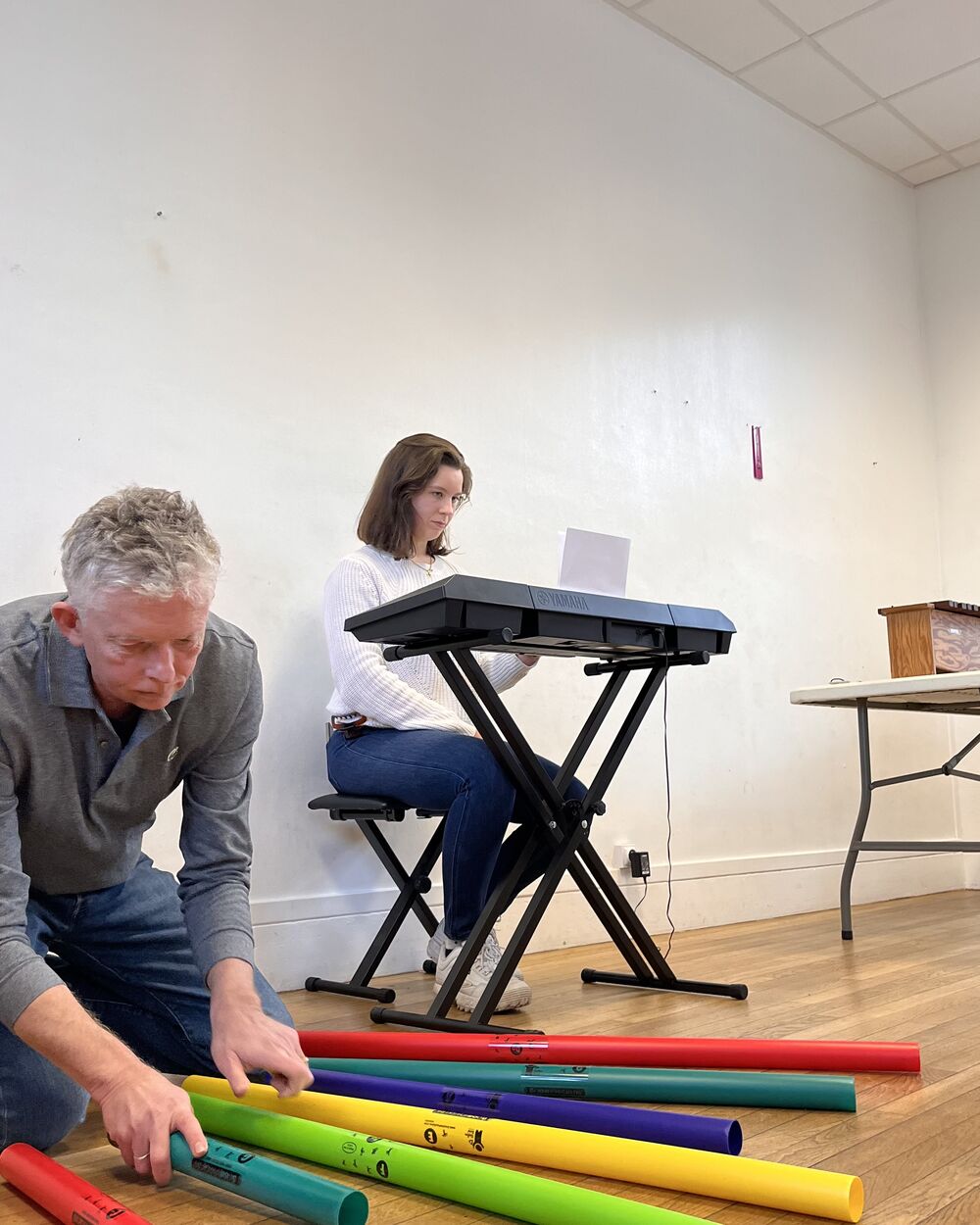 Un participant aligne les tubes sonores colorés, une participante au clavier